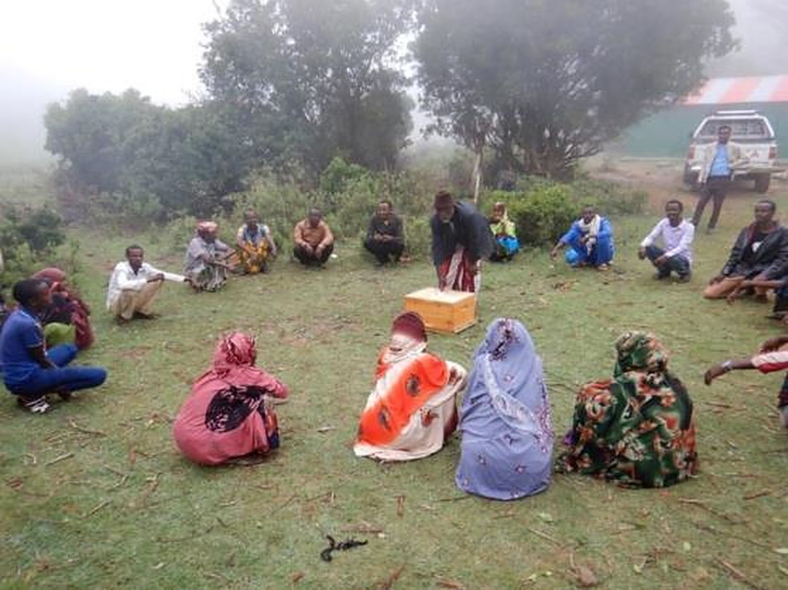 Community members seated in a circle during a meeting outdoors