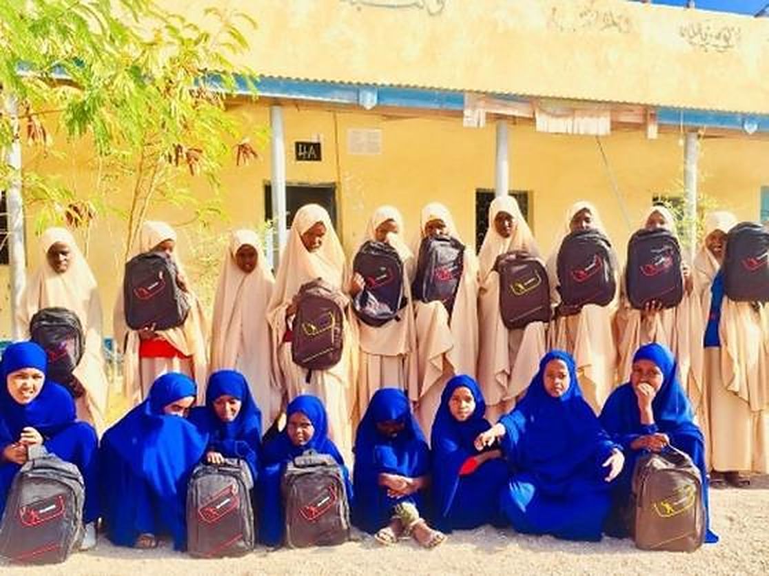 Schoolgirls holding new school bags outside their school